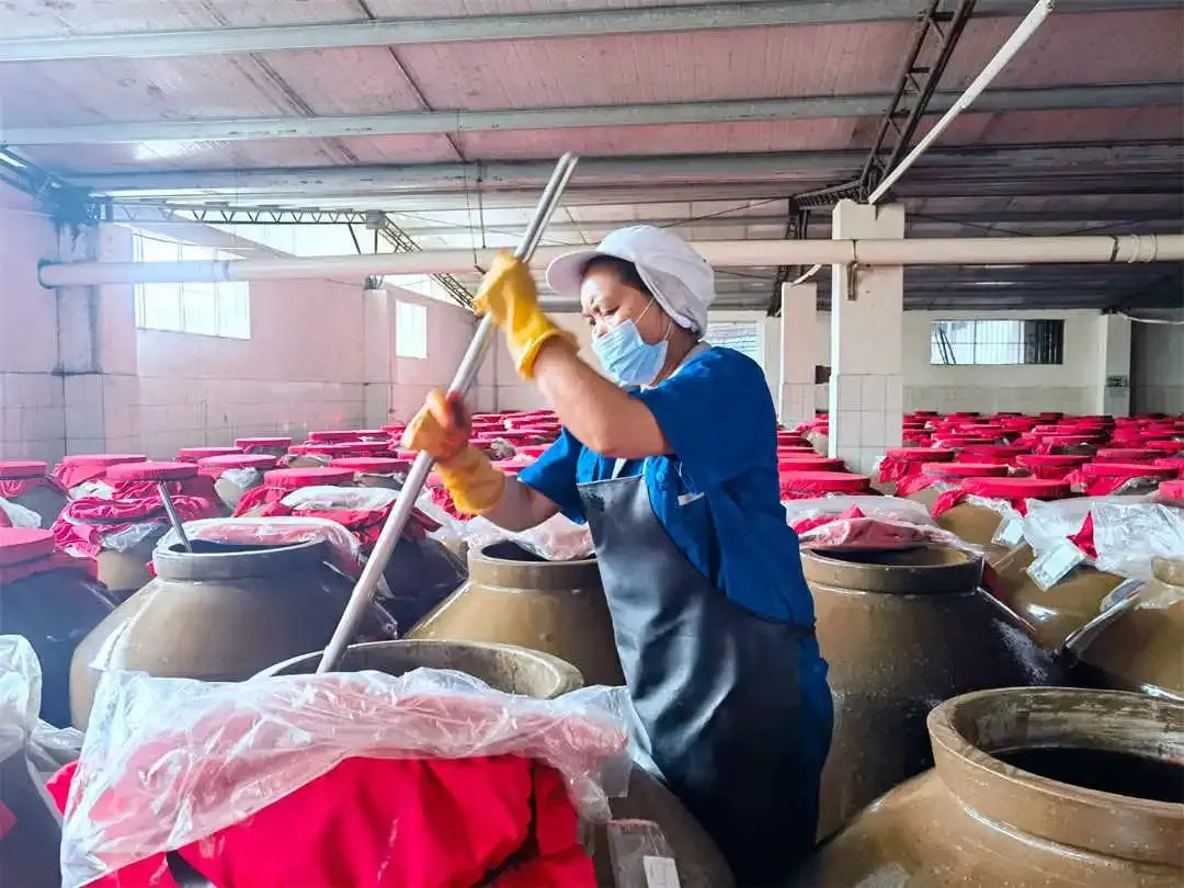 Рабочий на заводе Mingyang Food Co., Ltd. в уезде Мацзян перемешивает ферментированный кислый суп.