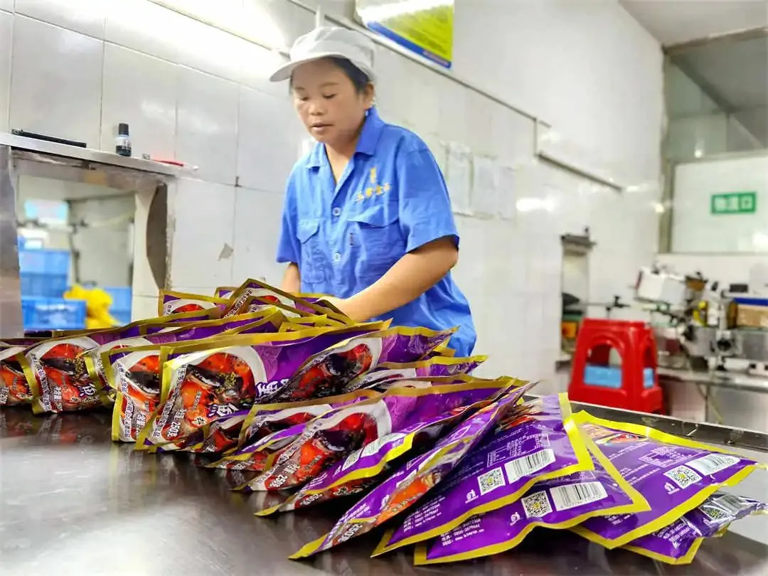 Рабочий на заводе Mingyang Food Co., Ltd. в уезде Мацзян упаковывает приправы для кислого рыбного супа.